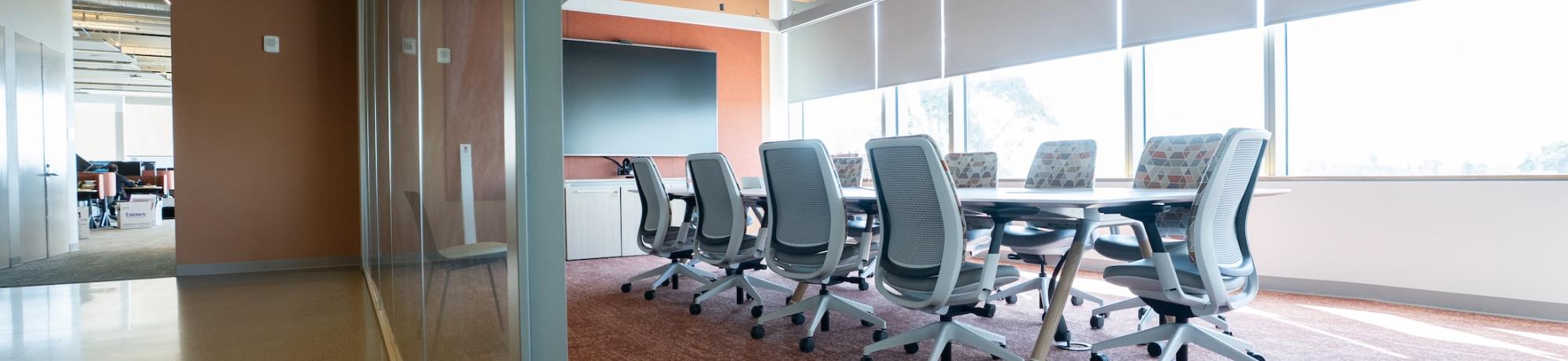 Modern empty conference room with long table, swivel chairs, and large windows